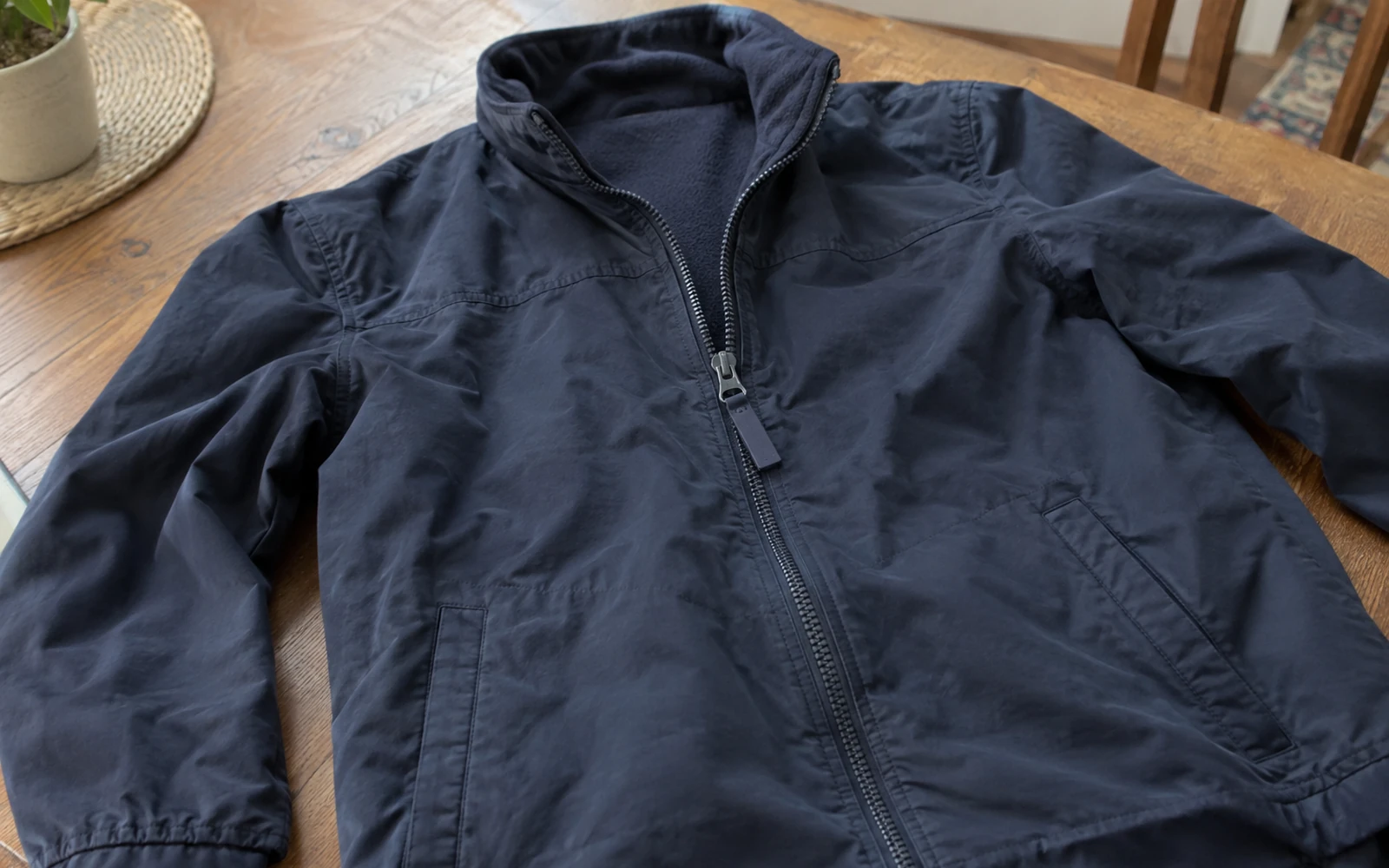 Veste marine posée à plat, fermeture partiellement fermée.